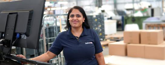 Paragon employee standing at screen with boxes and mail crates behind her