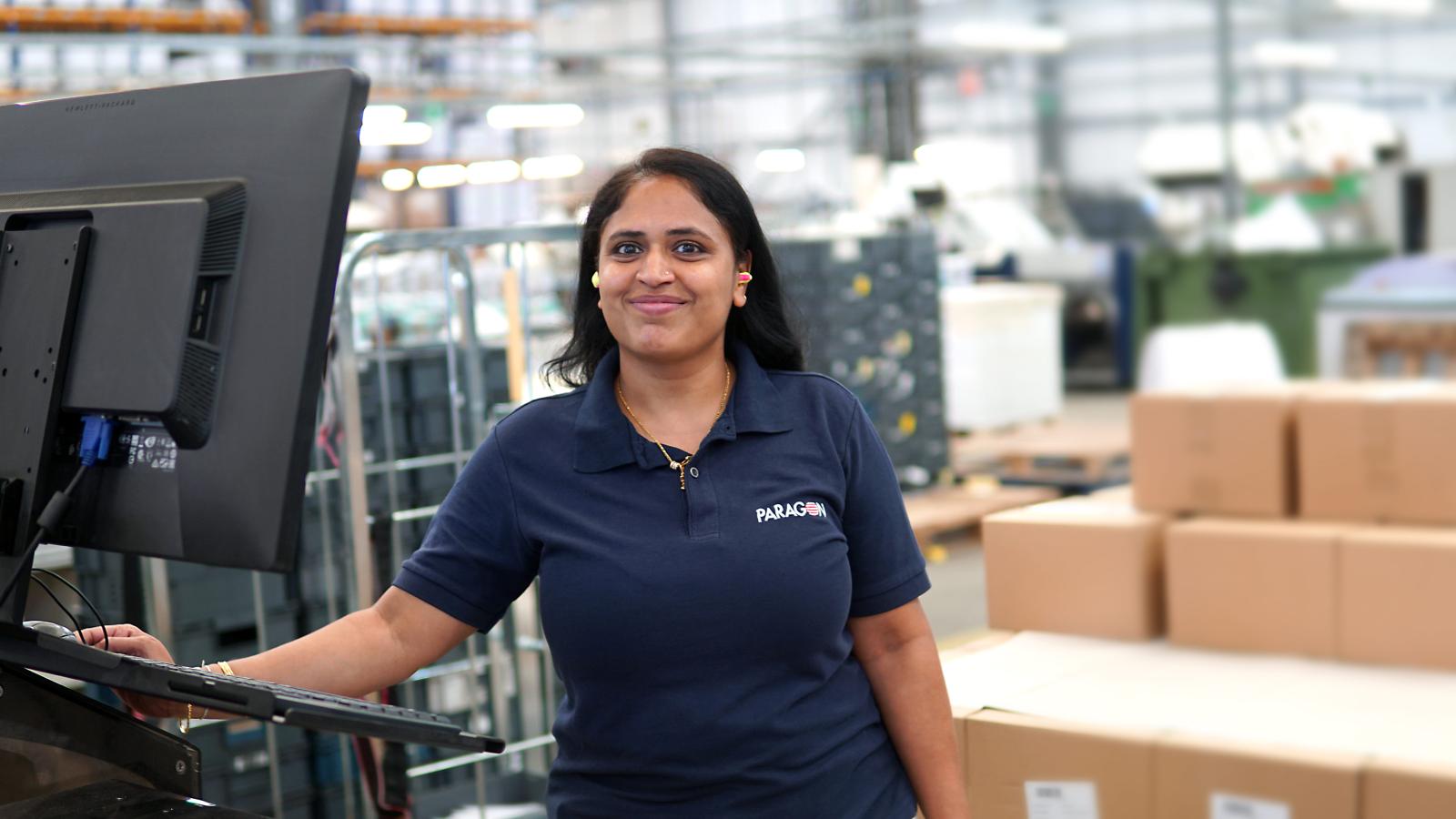 Paragon employee standing at screen with boxes and mail crates behind her